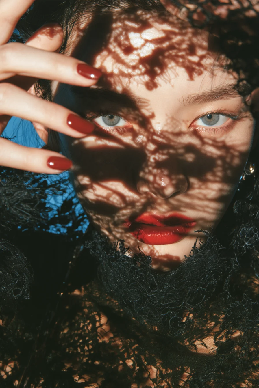A veil of black lace draped over a face, red lips showing through